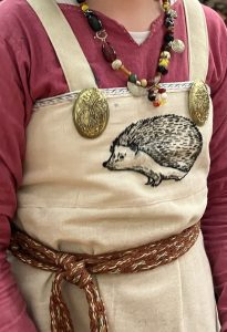 Cosima's viking apron dress, embroidered with a hedgehog, made by Milgrim