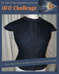 A black wool, capped sleeved gonete in the style of 1572 Castille on a beige dressform in front of a curtain